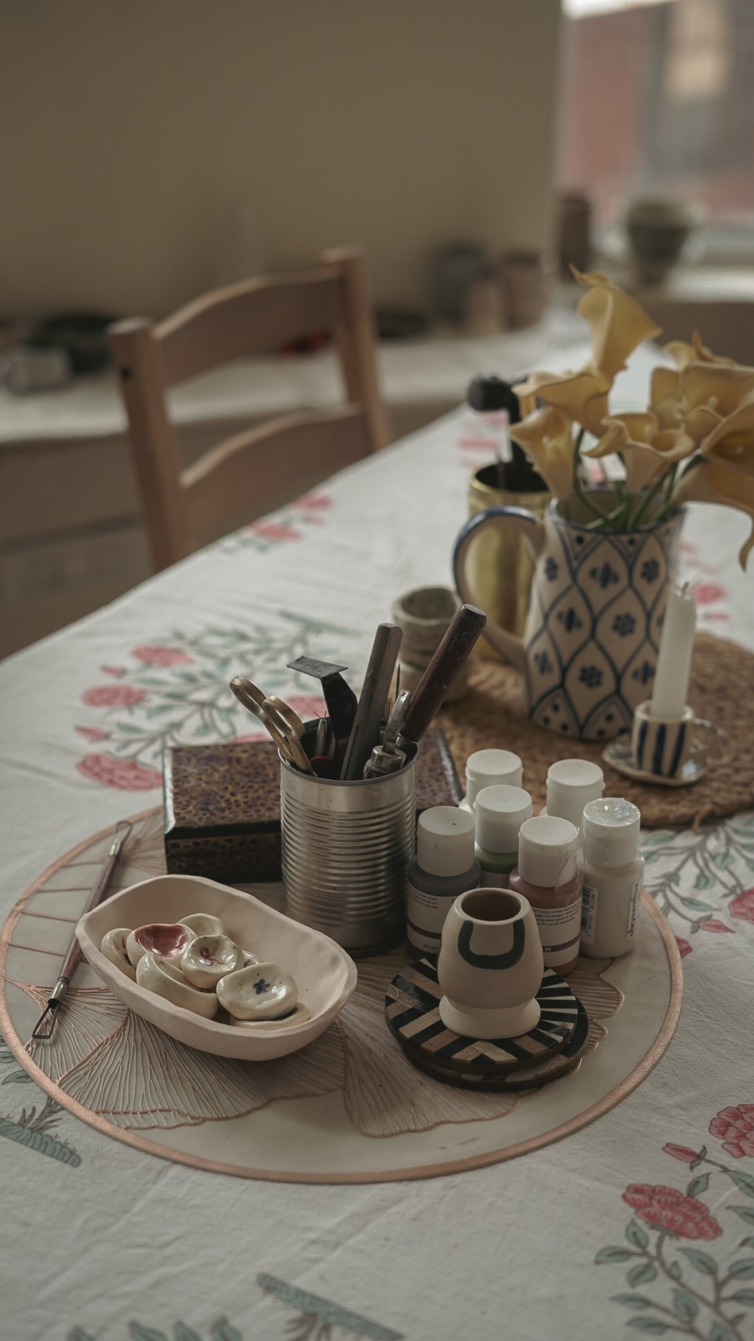 Pottery tools and handmade pieces on a floral tablecloth